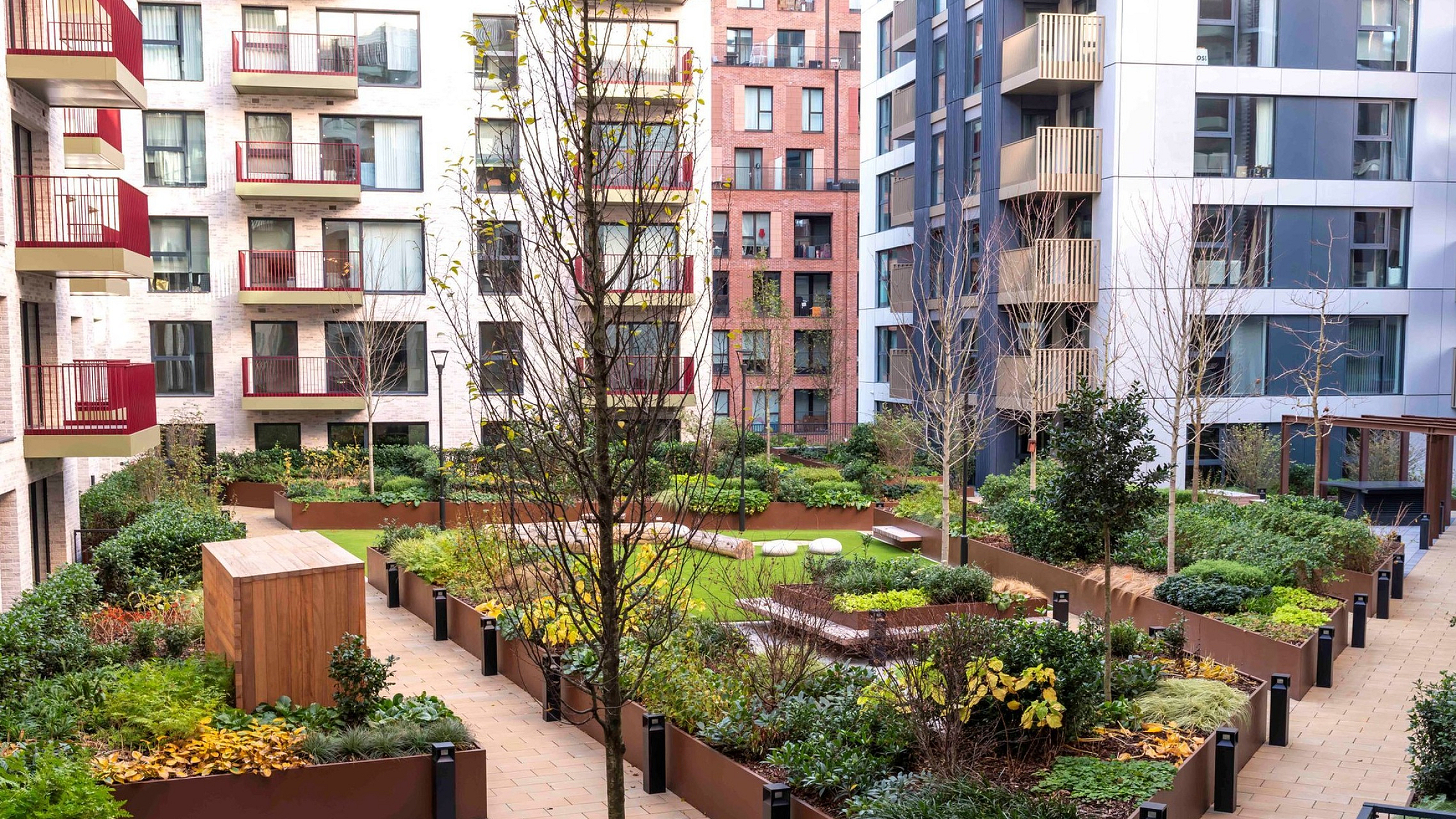 Modern apartment complex featuring lush landscaped courtyard with vibrant greenery, walking paths, and contemporary architectural design.