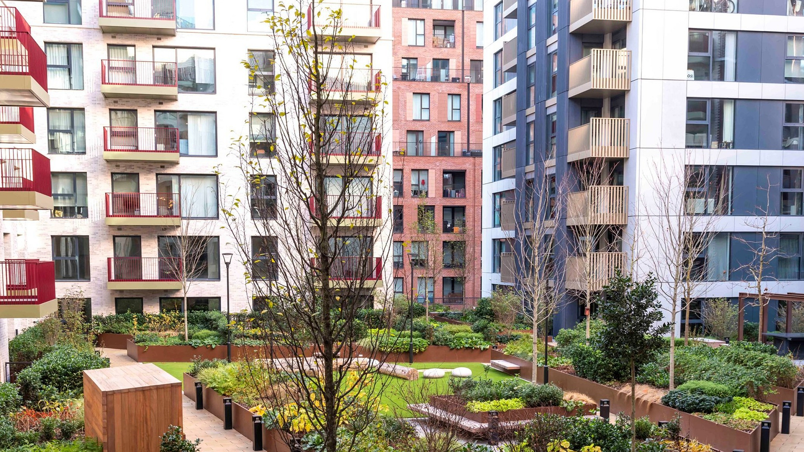 Vibrant urban courtyard showcasing lush gardens and modern apartment balconies, offering a serene escape in the city.