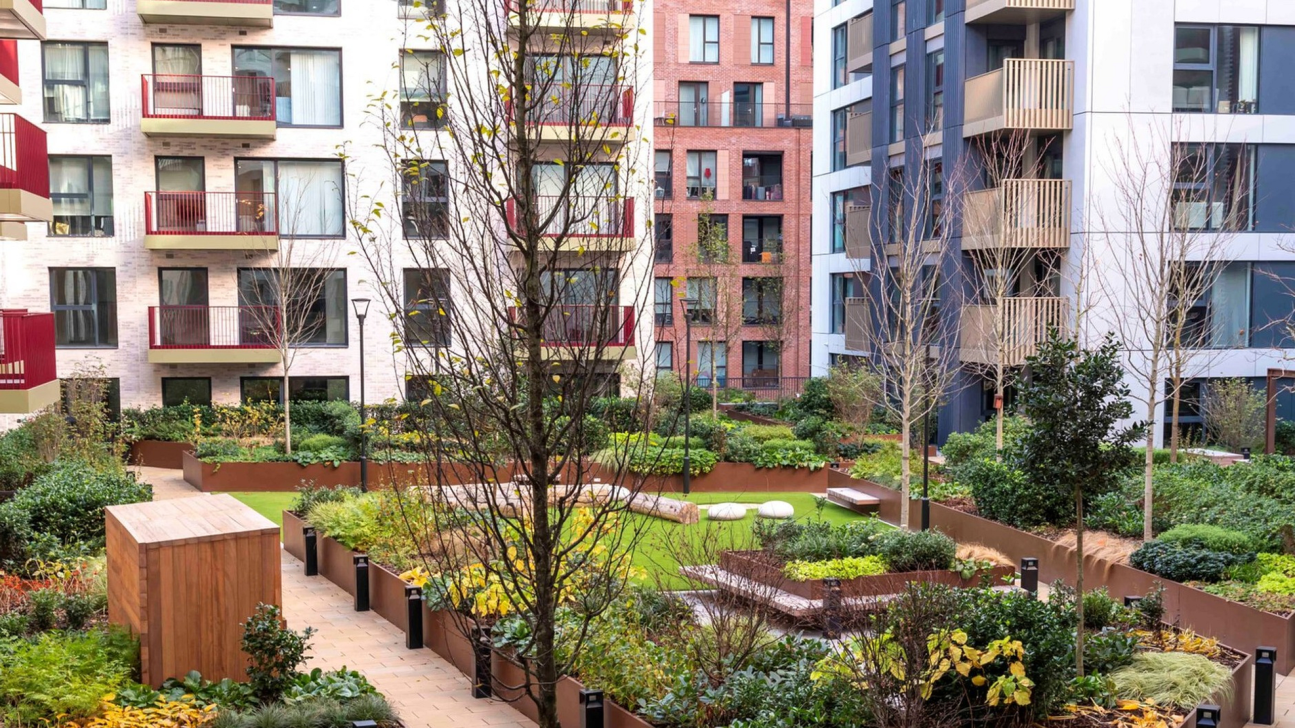Chic urban apartment courtyard with lush gardens, modern landscaping, and vibrant planters surrounded by contemporary buildings.