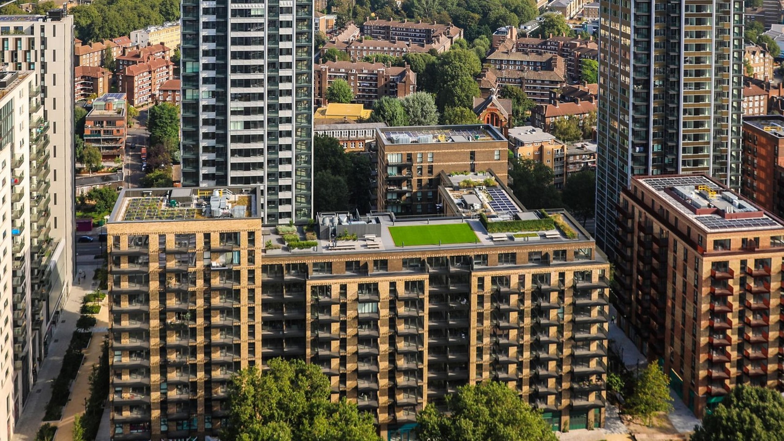Stunning aerial view of modern skyscrapers amidst lush greenery, showcasing vibrant urban living in a thriving cityscape.