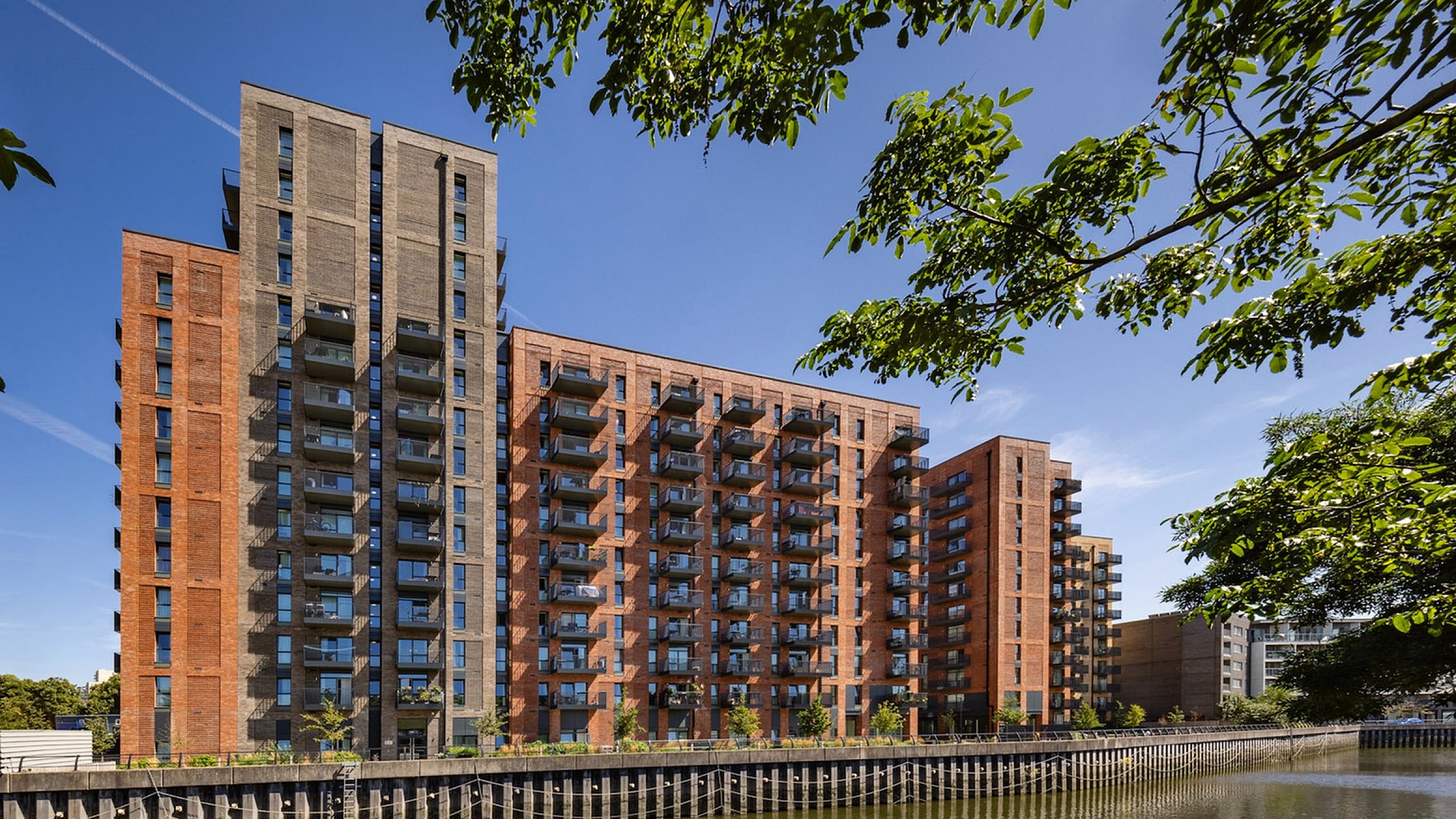 Contemporary riverside apartment complex featuring sleek architecture and vibrant surroundings, perfect for modern urban living.