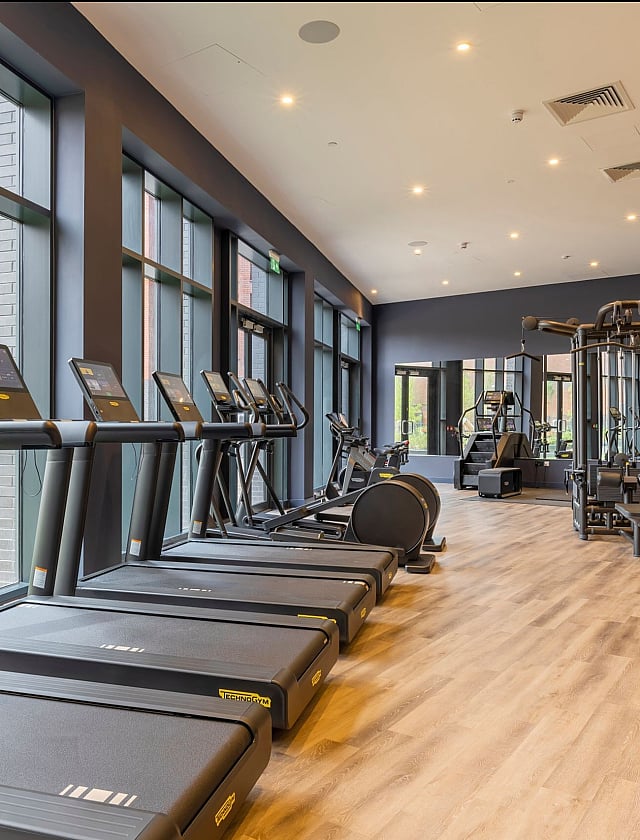 Modern fitness center with state-of-the-art treadmills and exercise equipment, featuring floor-to-ceiling windows for natural light.