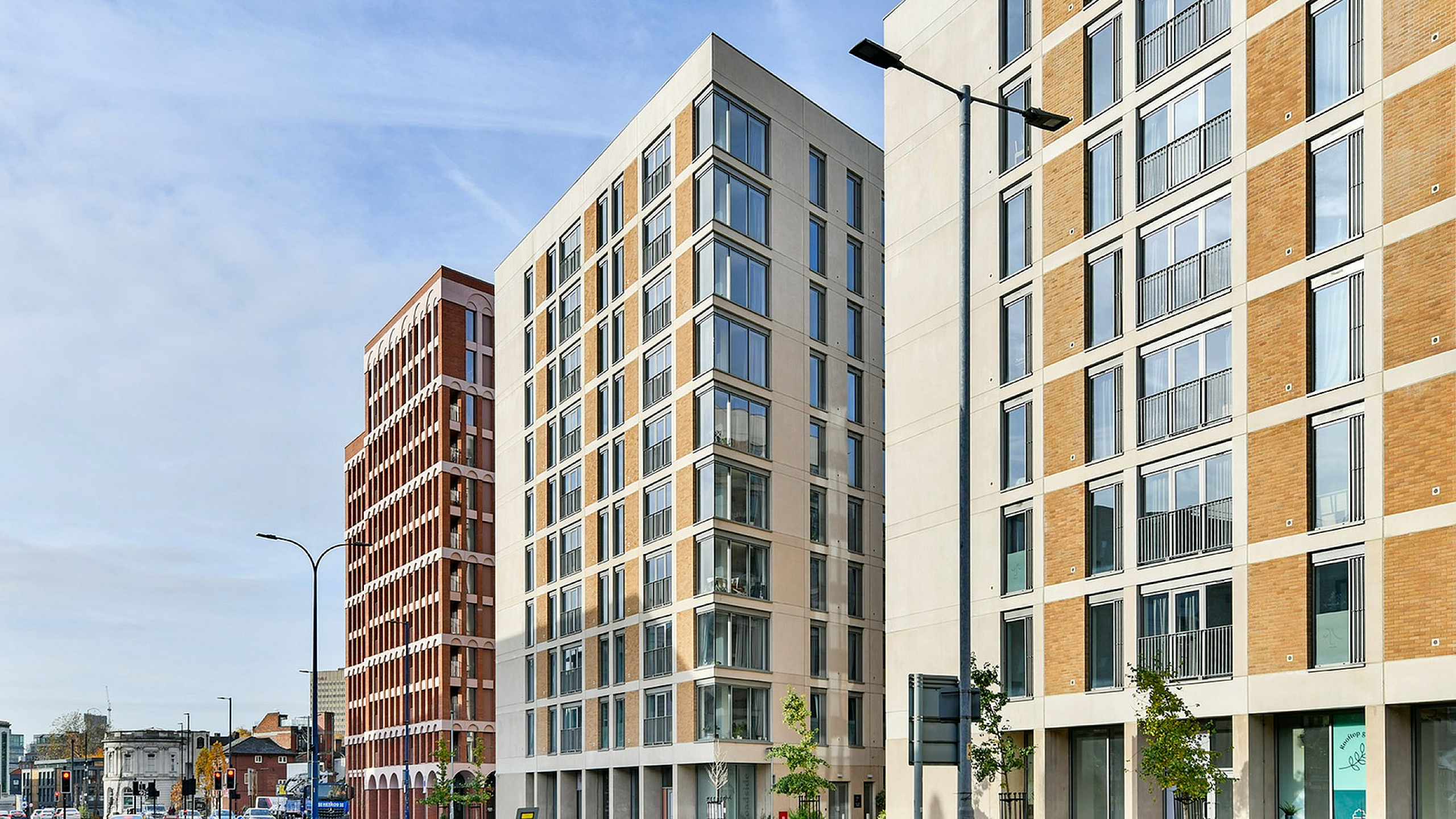 Modern urban apartment complex with sleek architectural design featuring large windows and vibrant street setting.